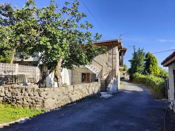 Fachada de piedra de Casa Elena y calle del pueblo en Ourense
